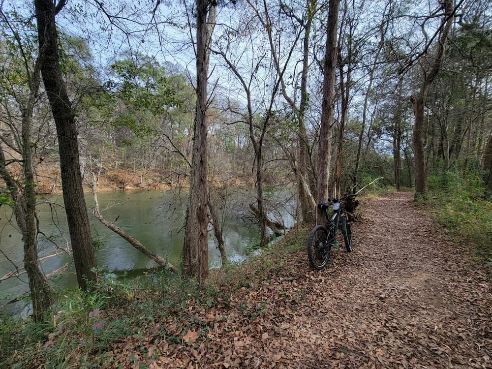 a bicycle parked on a trail on the edge of a river