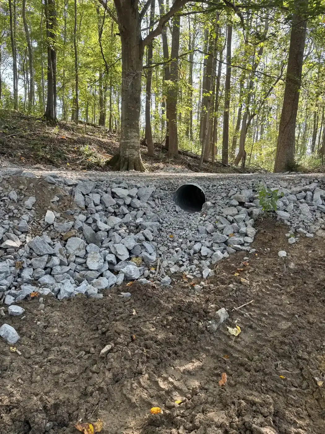 Completed culvert crossing with rip-rap and a shaped ditch below the rebuilt woods road in Westmoreland, TN